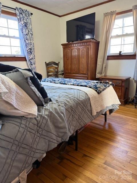 bedroom featuring multiple windows, light wood-style floors, and ornamental molding