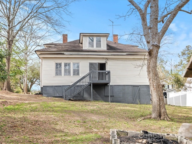 back of property with a shingled roof, fence, a lawn, and a chimney