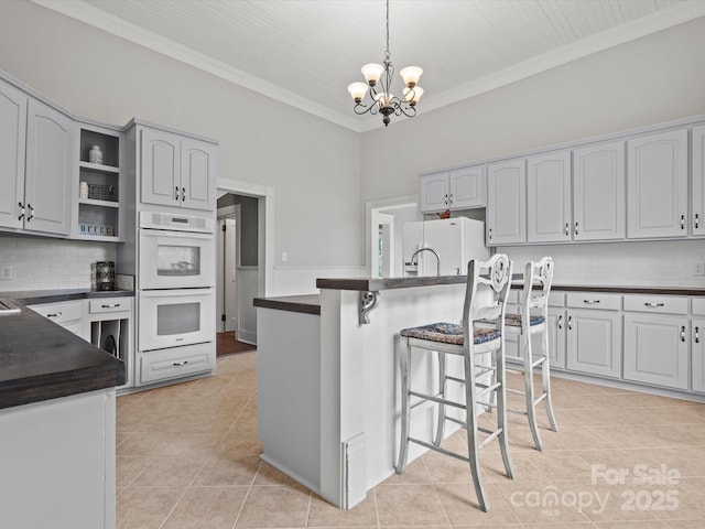 149 Crescent Dr, Chesterfield, SC 29709 - kitchen featuring a notable chandelier, a kitchen breakfast bar, white appliances, dark countertops, and decorative backsplash