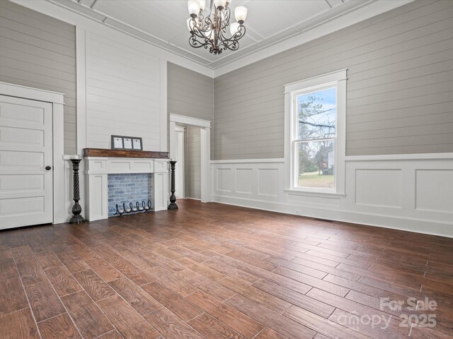149 Crescent Dr, Chesterfield, SC 29709 - unfurnished living room featuring a fireplace, an inviting chandelier, a decorative wall, ornamental molding, and dark wood-style flooring