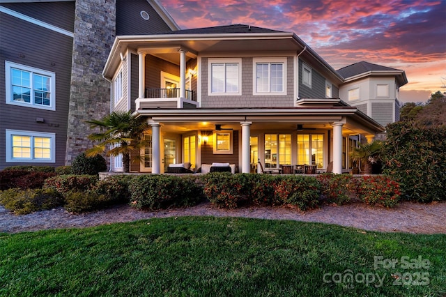 exterior space with an outdoor living space, a balcony, a ceiling fan, and a lawn