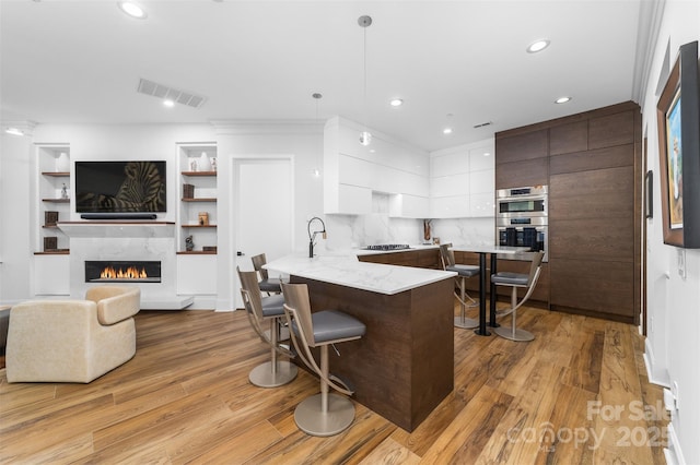 kitchen featuring visible vents, white cabinetry, a peninsula, a kitchen bar, and modern cabinets