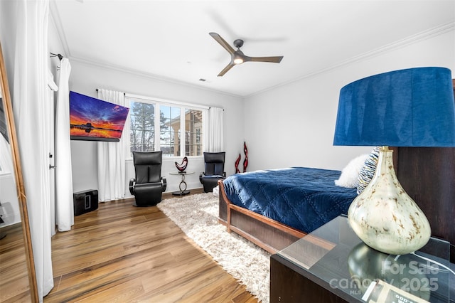 bedroom featuring ceiling fan, wood finished floors, and crown molding