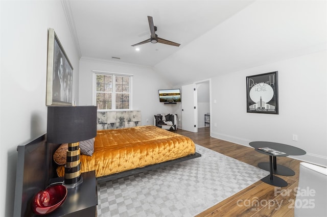 bedroom with lofted ceiling, a ceiling fan, wood finished floors, crown molding, and baseboards