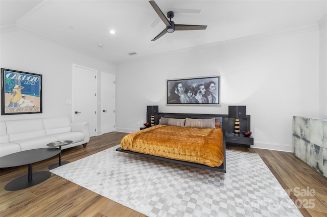 bedroom with wood finished floors, visible vents, and ornamental molding