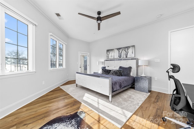 bedroom featuring visible vents, a ceiling fan, wood finished floors, crown molding, and baseboards