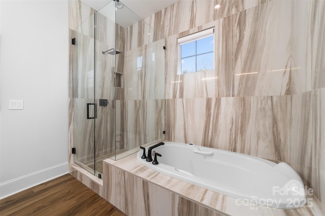 bathroom with wood finished floors, baseboards, a marble finish shower, tile walls, and a bath