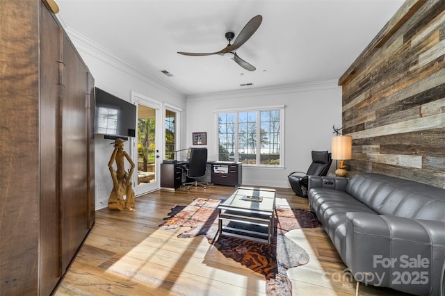 living room featuring a wealth of natural light, visible vents, wood finished floors, crown molding, and ceiling fan