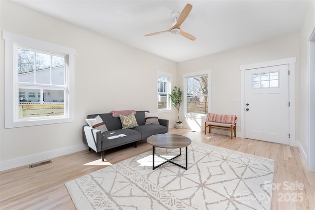 living room featuring a wealth of natural light, visible vents, a ceiling fan, and wood finished floors