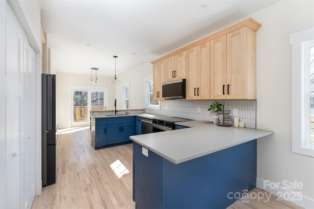 kitchen featuring light brown cabinetry, decorative backsplash, a peninsula, range with electric stovetop, and a sink