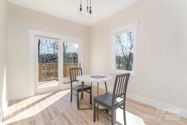 dining space with light wood-style flooring, baseboards, and a wealth of natural light