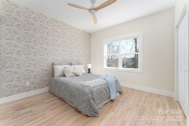 bedroom with ceiling fan, wallpapered walls, baseboards, and wood finished floors