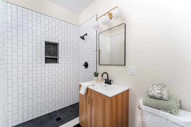 full bath featuring toilet, vanity, and a tile shower