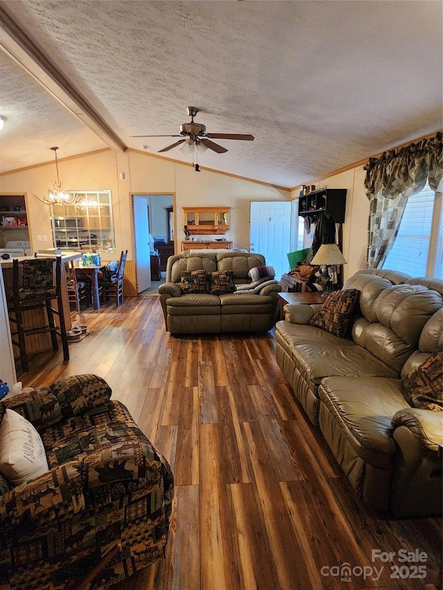 living area with ceiling fan with notable chandelier, lofted ceiling with beams, a textured ceiling, wood finished floors, and crown molding