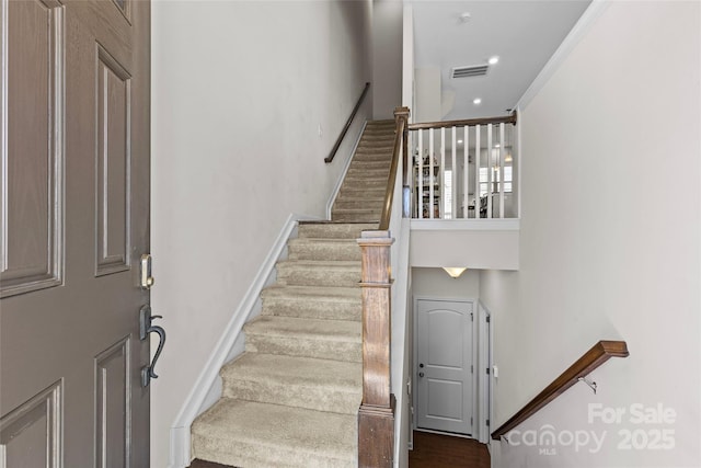 stairway with visible vents, baseboards, and wood finished floors