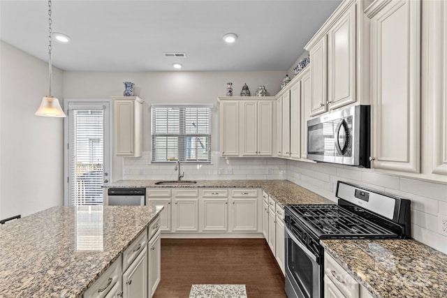 kitchen with dark wood-type flooring, a sink, stainless steel appliances, white cabinets, and decorative backsplash