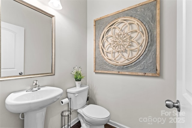 half bathroom with baseboards and toilet