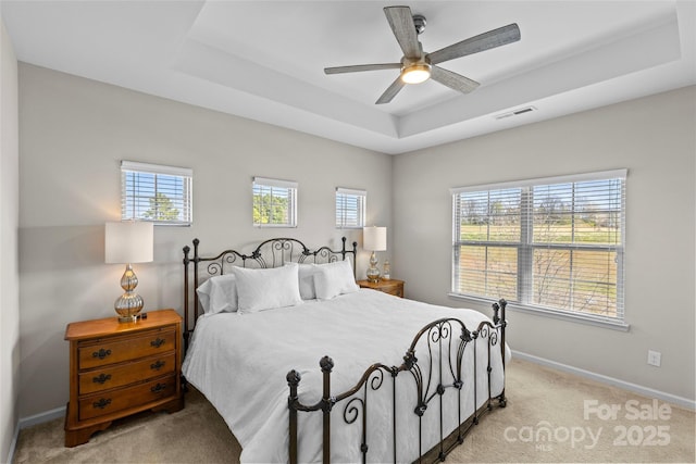 bedroom featuring visible vents, baseboards, ceiling fan, a raised ceiling, and light colored carpet