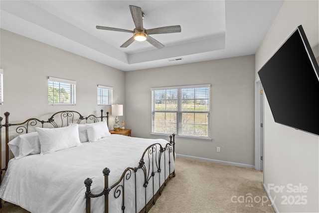 bedroom with baseboards, a tray ceiling, light carpet, and visible vents