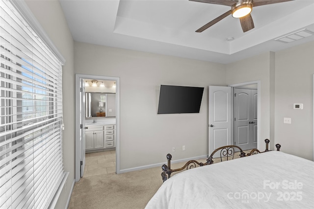 bedroom with light carpet, visible vents, baseboards, and a tray ceiling