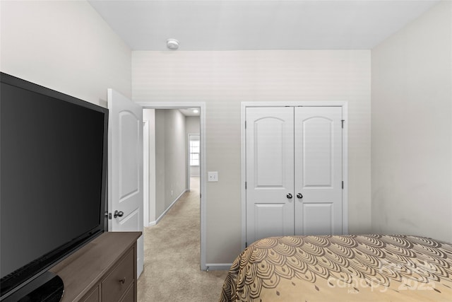 bedroom with light colored carpet, a closet, and baseboards