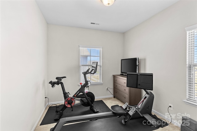 exercise area featuring visible vents, baseboards, and light colored carpet