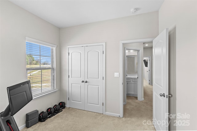 bedroom with light colored carpet, a closet, and baseboards