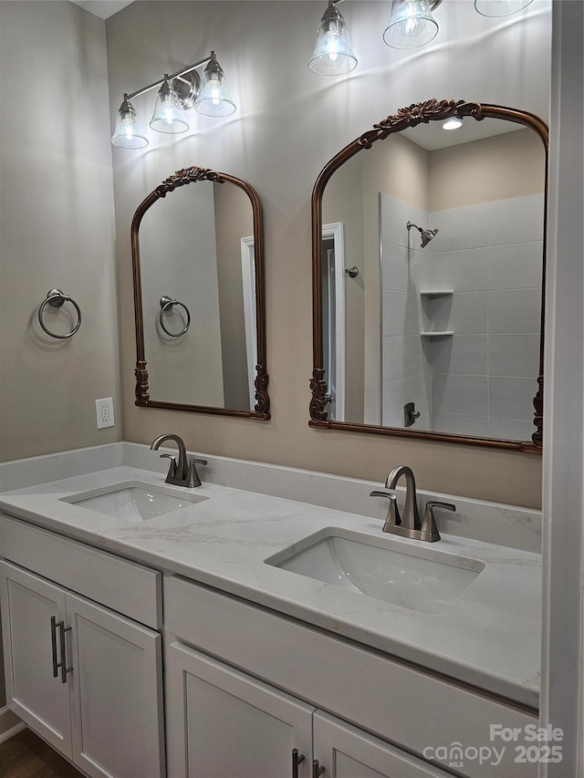 bathroom with a sink, tiled shower, and double vanity