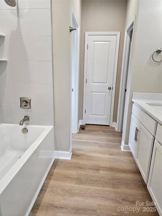 full bathroom with washtub / shower combination, baseboards, wood finished floors, and vanity