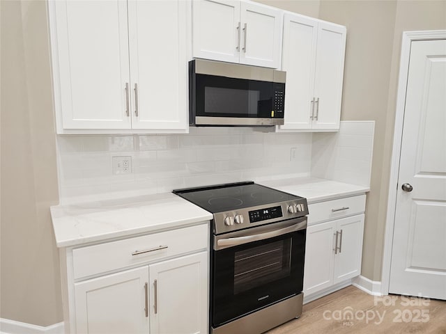 kitchen featuring stainless steel appliances, light stone countertops, white cabinets, and light wood finished floors