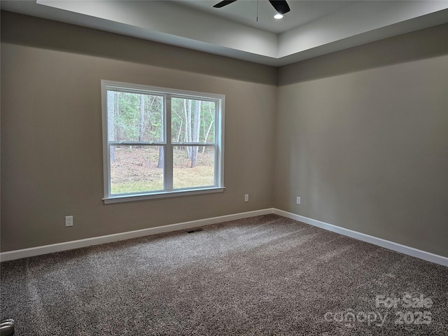 spare room with baseboards, dark carpet, and ceiling fan