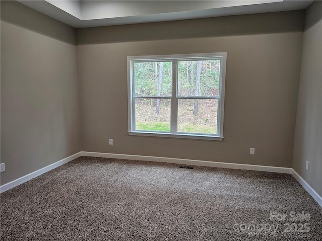 empty room with visible vents, baseboards, and dark carpet