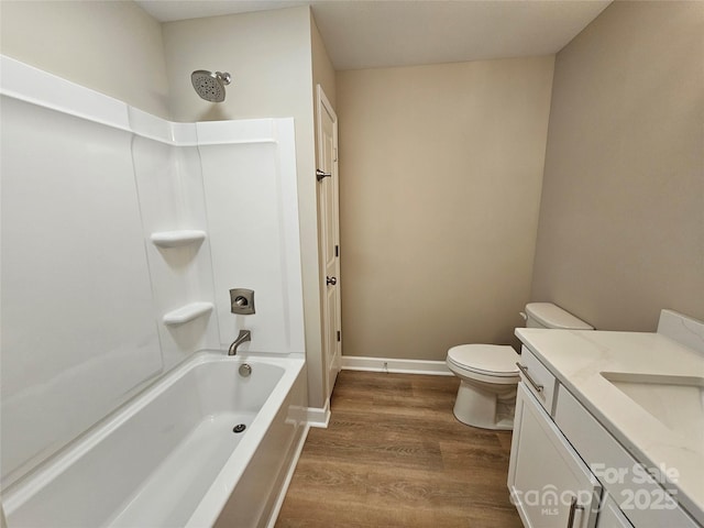 full bathroom featuring toilet, shower / tub combination, wood finished floors, baseboards, and vanity