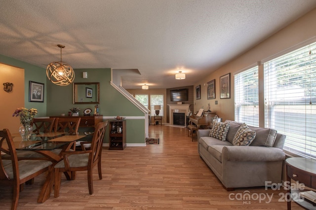 dining space with a fireplace, a textured ceiling, light wood-type flooring, and baseboards