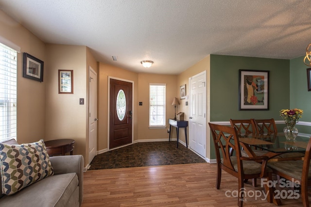 entryway featuring a textured ceiling, baseboards, and wood finished floors