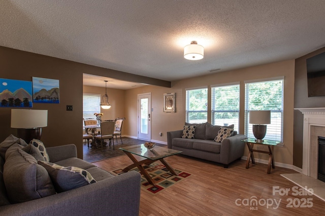 living area featuring a wealth of natural light, a premium fireplace, visible vents, and wood finished floors