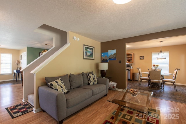 living area with baseboards, a textured ceiling, wood finished floors, and stairs