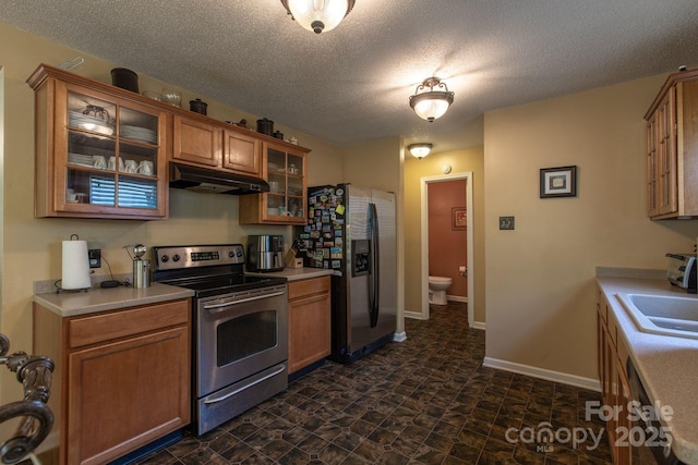 kitchen with a sink, light countertops, under cabinet range hood, and stainless steel appliances