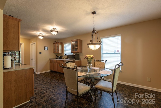 dining room with a textured ceiling, baseboards, and stone finish flooring