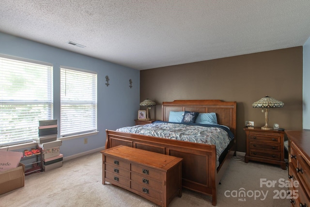 bedroom with a textured ceiling, light colored carpet, visible vents, and baseboards