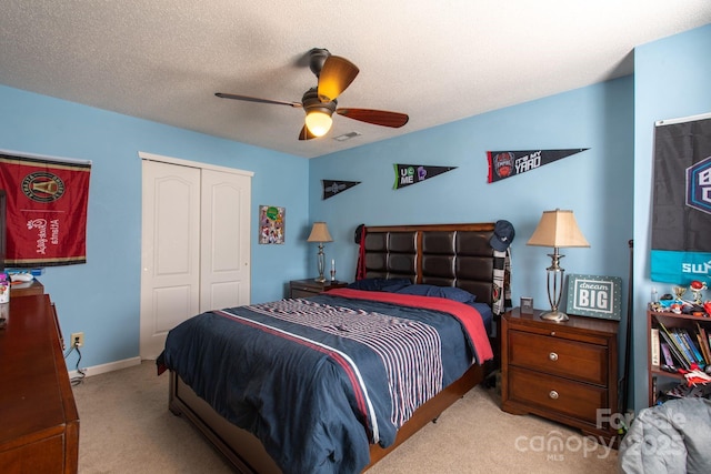 carpeted bedroom featuring baseboards, visible vents, ceiling fan, a closet, and a textured ceiling