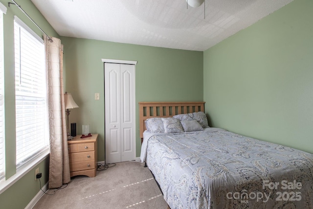 carpeted bedroom with ceiling fan, baseboards, a closet, and a textured ceiling