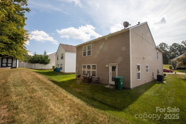 rear view of house with central air condition unit, a lawn, fence, a storage shed, and an outdoor structure