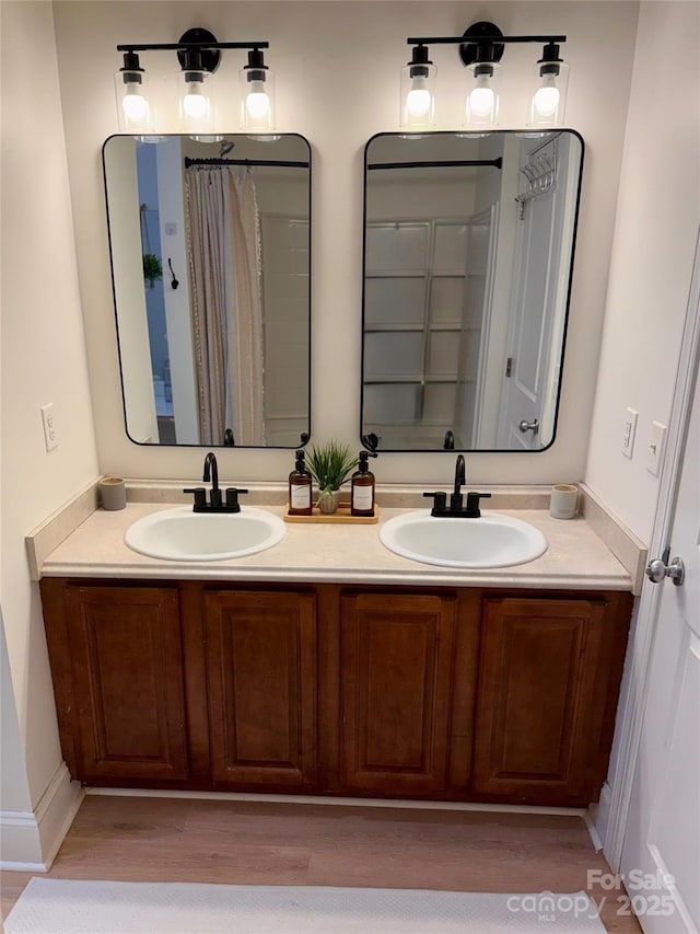 bathroom featuring double vanity, wood finished floors, and a sink