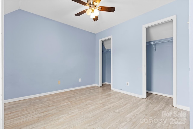 unfurnished bedroom with baseboards, light wood-style floors, multiple closets, and a ceiling fan