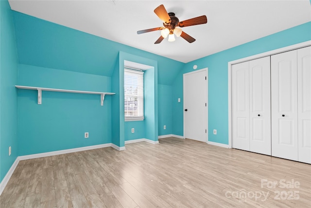 unfurnished bedroom with a ceiling fan, wood finished floors, a closet, baseboards, and vaulted ceiling