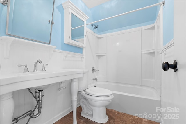 bathroom with a wainscoted wall, toilet, and bathtub / shower combination