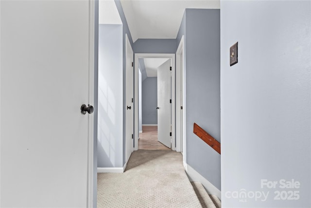 corridor featuring baseboards and carpet floors