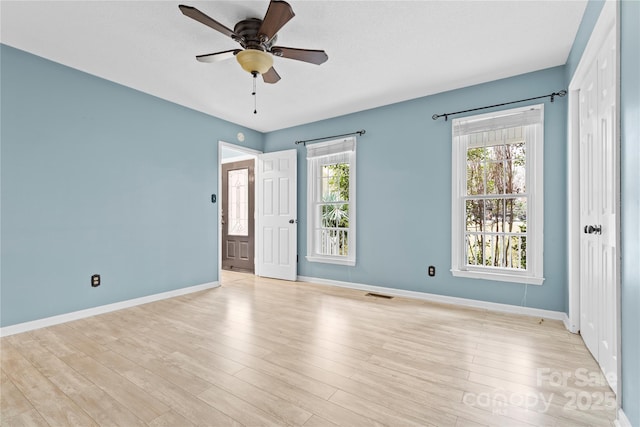 empty room featuring light wood-type flooring, visible vents, baseboards, and ceiling fan