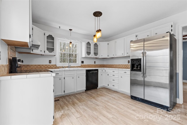 kitchen featuring light wood finished floors, dishwasher, stainless steel refrigerator with ice dispenser, white cabinets, and a sink